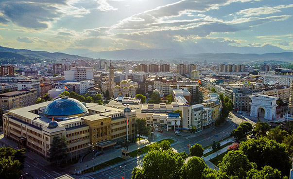 Blick von oben auf die Hauptstadt Skopje mit Bergen im Hintergrund.